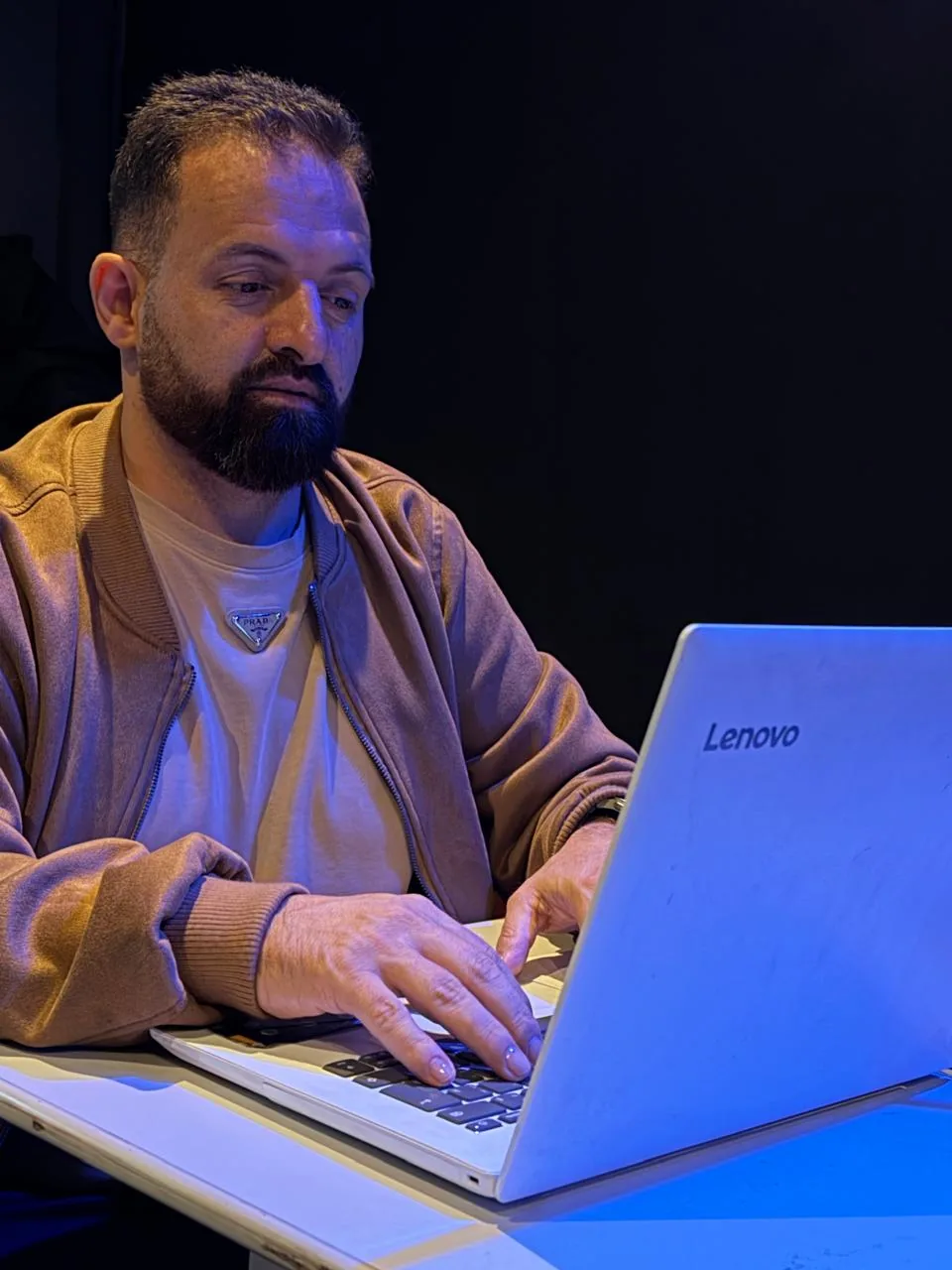 Evaldo Claro sentado, com as mãos sobre o teclado de um notebook.